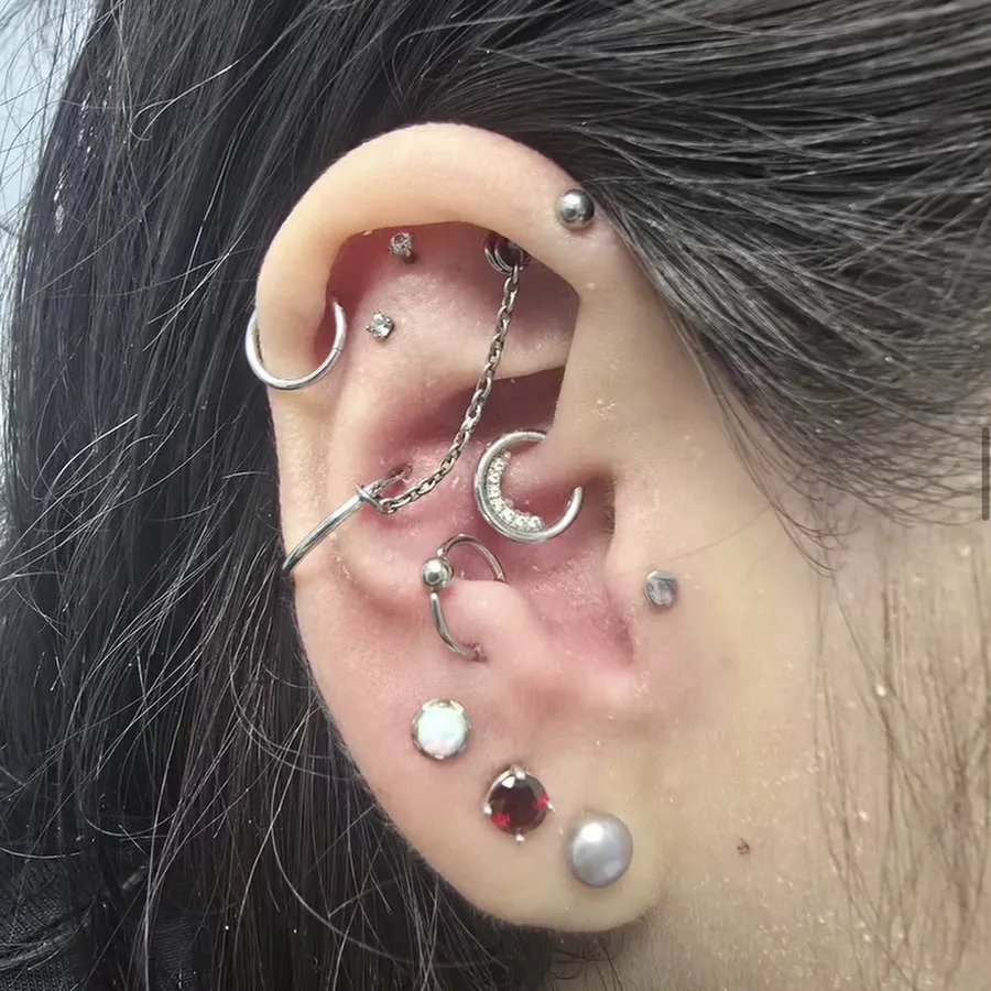 Ear with a curated stack: helix, conch, daith chain and lobes